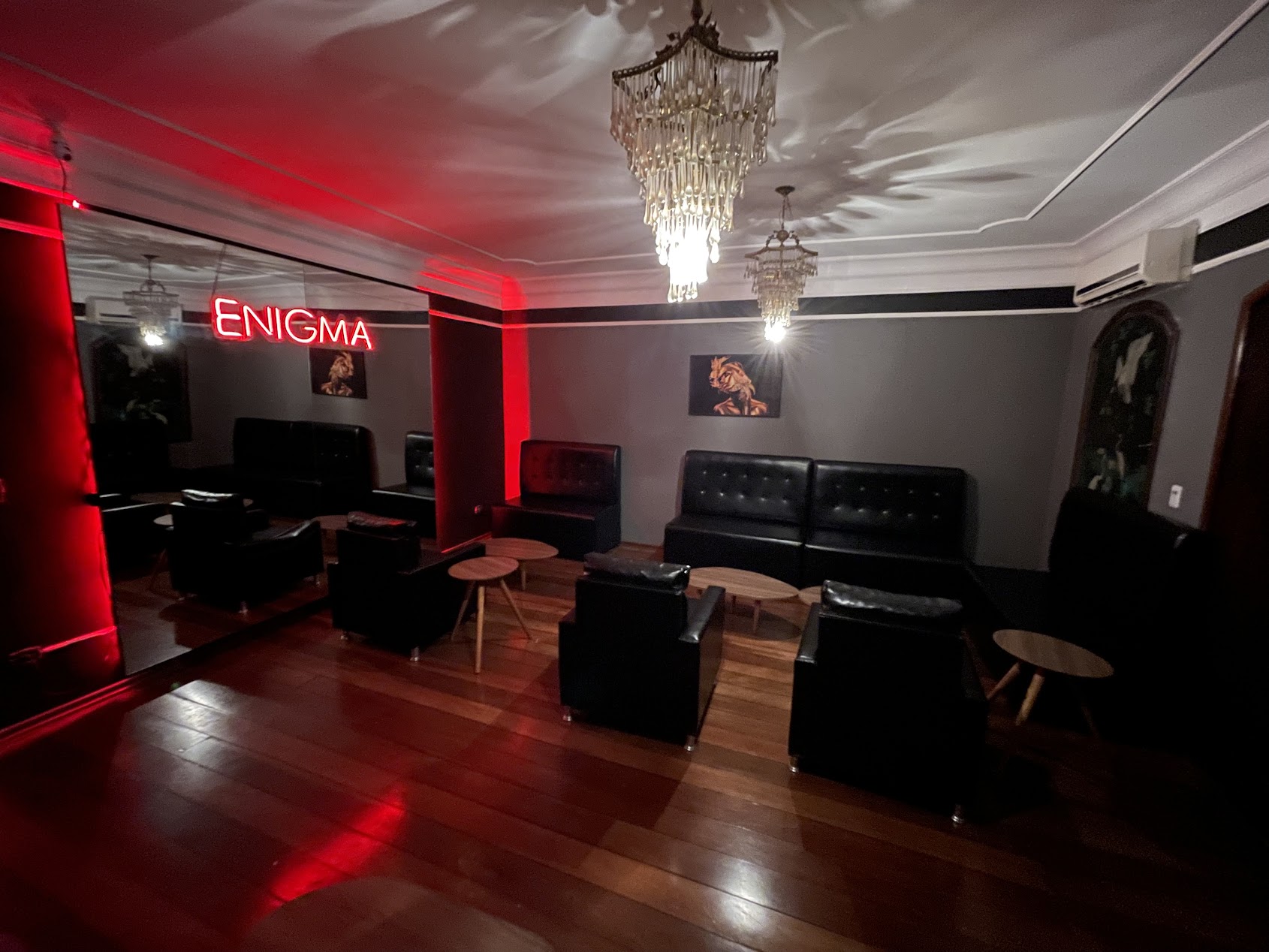 Lounge interno da Enigma com sofás e lustres